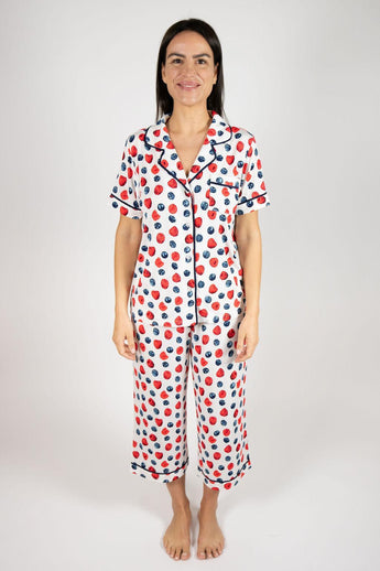 Ivory short-sleeve pajama top and matching cropped pants with red and navy berries print, notch collar, navy piping, front view