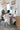 Woman sitting at a vanity mirror wearing Aspen Dream's Nora short robe in ivory