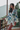 model wearing the Clea short robe by Marjolaine with a wrap front and self-tie belt in white with floral design