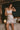 Model wearing the Marjolaine Tess Silk Nighty in ivory featuring smooth silk satin, floral Calais lace at the neckline and hem, adjustable spaghetti straps, and an elegant above-the-knee silhouette.