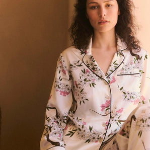 Model wearing the Olivia von Halle Lila Ana Ivory Blossom silk pajama set featuring the delicate Blossom floral print on ivory silk satin with black contrast piping.