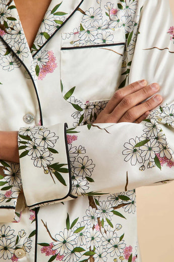 Close-up of the Olivia von Halle Lila Ana Ivory Blossom silk pajama shirt highlighting the Blossom floral print, black contrast piping, signature buttons, and 19 momme silk satin.