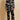 Model wearing the Olivia von Halle Lila Rene Black Blossom silk pajama set featuring the exclusive Blossom floral print on black silk satin with ivory contrast piping.