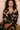 Model wearing the Olivia von Halle Lila Rene Black Blossom silk pajama set featuring the exclusive Blossom floral print on black silk satin with ivory contrast piping.