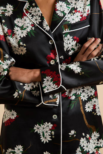 Close-up of the Olivia von Halle Lila Rene Black Blossom silk pajama shirt highlighting the Blossom floral print, ivory contrast piping, signature buttons, and luxurious silk satin.