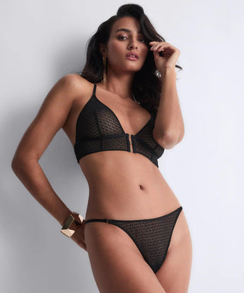 Model wearing the Secret Language Triangle Bra & Thong by Aubade in Fantasy with a plunging neckline, longline underband, and minimal thong with gold eyelets