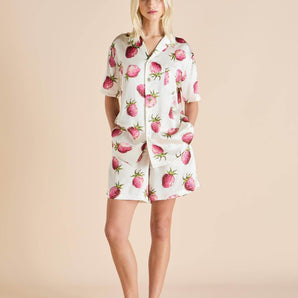 Short silk pajama set in strawberry print with elastic waist shorts and branded buttons, offering breezy fit and charming luxury.