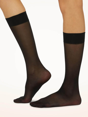 Model wearing Wolford Satin Touch 20 Knee-Highs in black showing sheer finish and comfort band