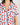 Close-up of notch collar, chest pocket, and button placket on ivory pajama top with berries print and navy piping