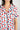 Close-up of notch collar, chest pocket, and button placket on ivory pajama top with berries print and navy piping