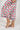 Close-up of cropped pant hem with navy piping trim and berries print