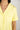 Close-up of notch collar, chest pocket, and button placket on buttery yellow pajama top with ruffled piping trim
