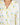 Close-up of notch collar and button placket on ivory pajama top with yellow tennis ball print and yellow piping trim