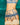 A close-up of a model wearing a blue lace lingerie set with matching garter straps and cream lace thigh-high stockings, posed against a dark green velvet background.