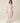 Model wearing blush pink Kenza Knitted Robe by Pluto with shawl collar and pom-pom trim .