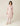 Model wearing blush pink Kenza Knitted Robe by Pluto with shawl collar and pom-pom trim .