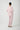 A person shown from the back wearing a light pink long-sleeve pajama top and matching jogger pants, standing against a plain light gray studio background.