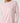 A close-up of a model wearing a light pink long-sleeve crewneck top with contrasting white trim at the collar and cuffs, paired with matching pink bottoms.