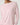 A close-up of a model wearing a light pink long-sleeve crewneck top with contrasting white trim at the collar and cuffs, paired with matching pink bottoms.