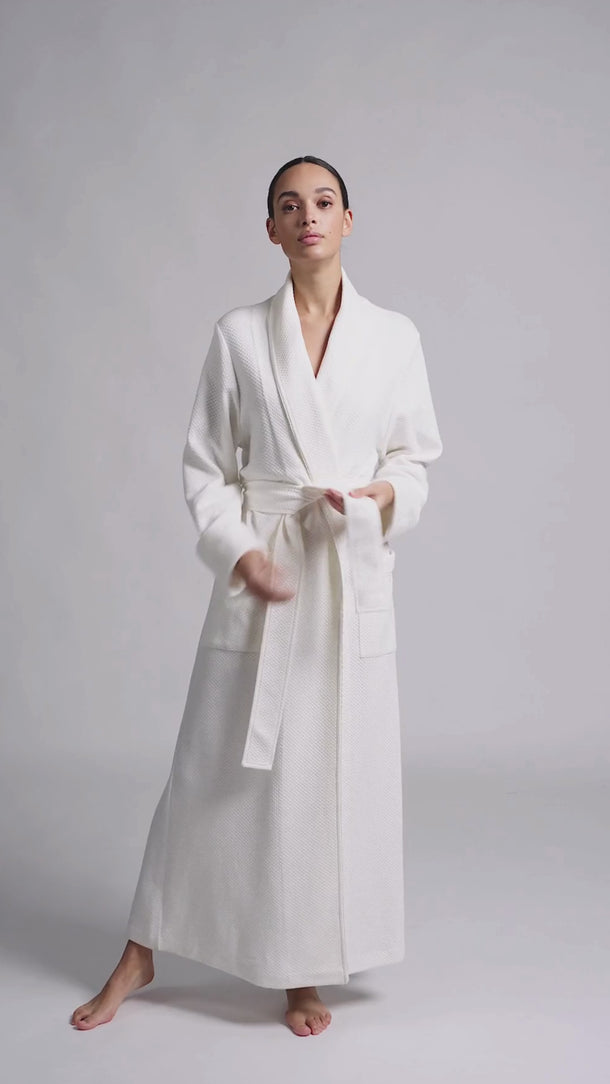 video of Model wearing Pluto Sylvie long robe in ivory with wrap design, matelassé fabric and belt