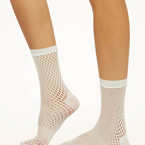 Model wearing Wolford Net Socks in white showing grid net pattern and ankle length